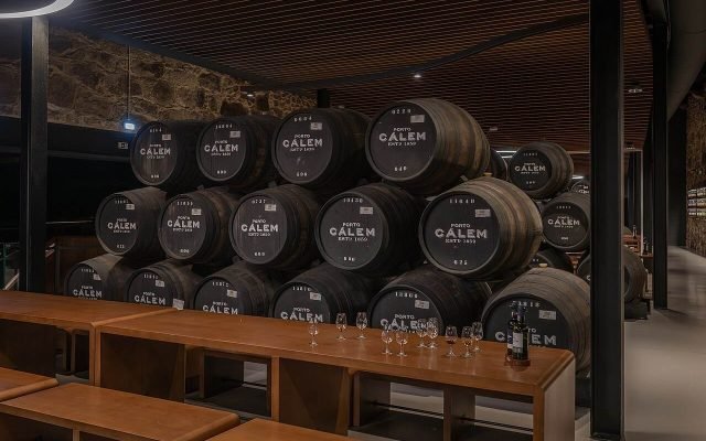 Rows of large oak port casks in a Vila Nova de Gaia cellar with a tasting area