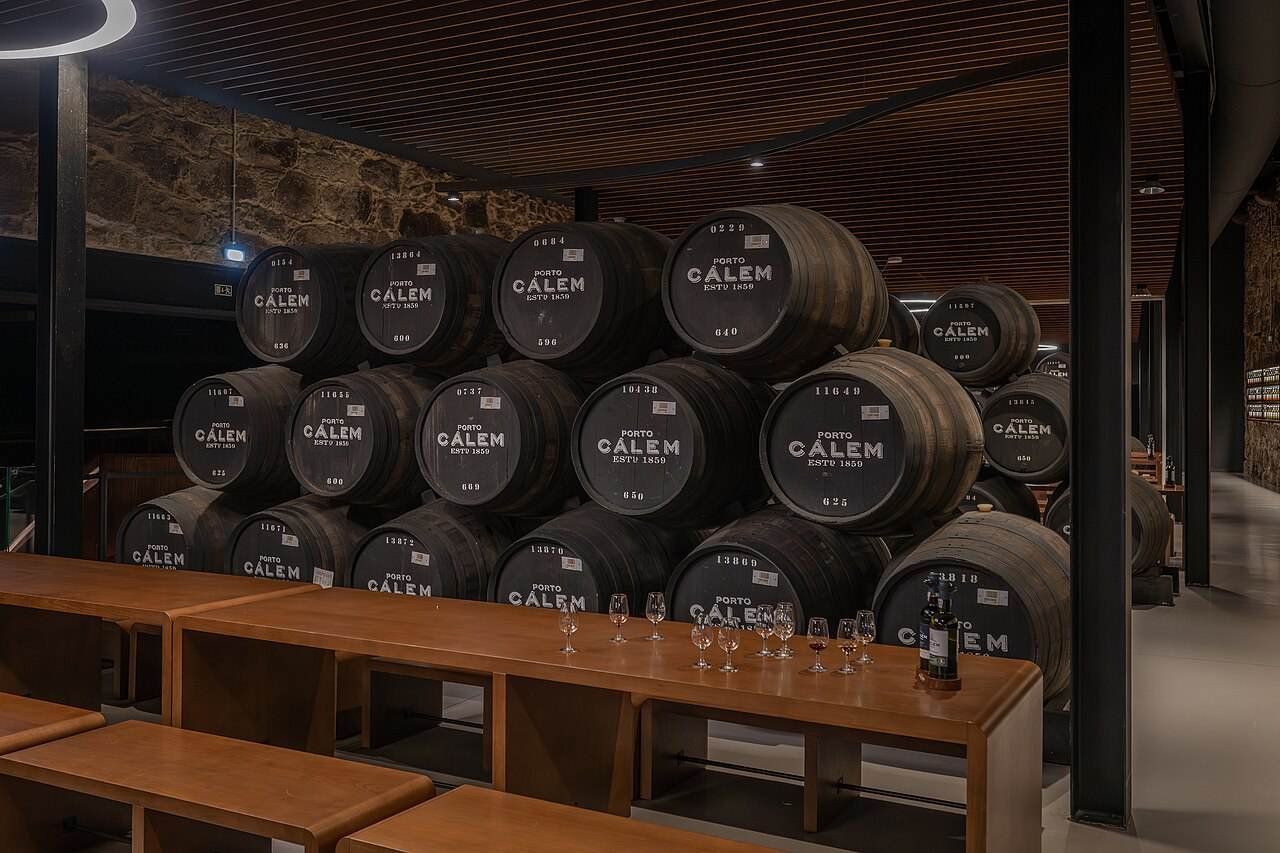Rows of large oak port casks in a Vila Nova de Gaia cellar with a tasting area
