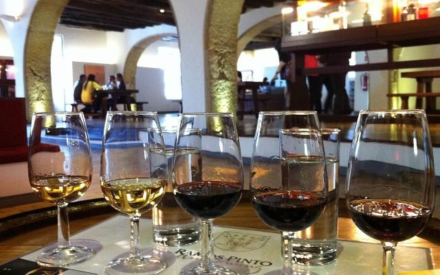 A row of glasses of white and red port lined up for a tasting