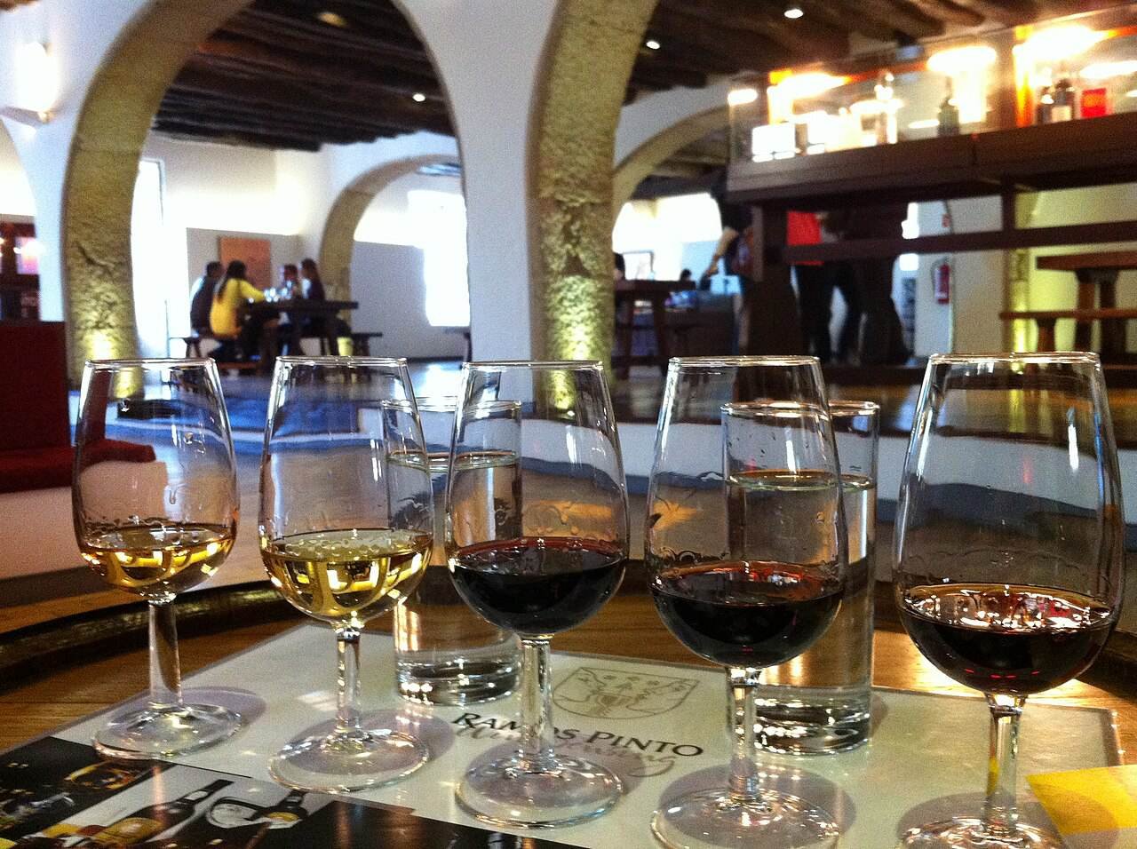 A row of glasses of white and red port lined up for a tasting